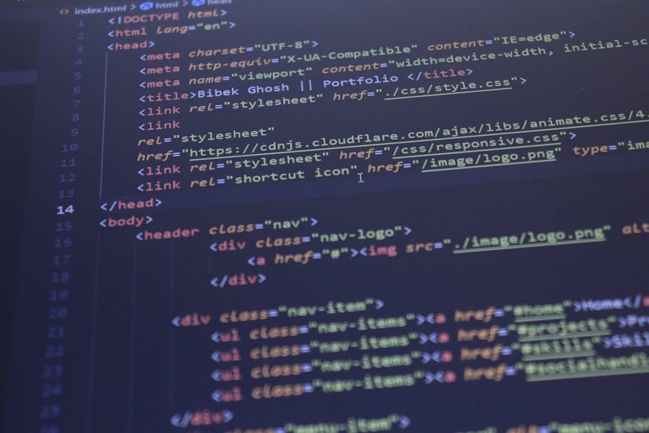 Close-up of a person's hands operating a laptop computer placed on a table, with the screen displaying code and software development environment. The individual is using a black keyboard with their ri